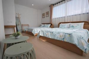 a bedroom with two beds and a table and a window at Dolce Home suratthani in Suratthani