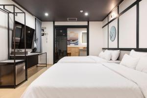 a bedroom with two white beds and a bathroom at Ryokan Stay in Gangneung
