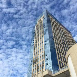 a tall glass building with a sky in the background at Ibis Dujiangyan in Dujiangyan