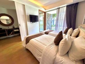 a hotel room with two beds and a television at Dealton Hotel Sanur in Sanur