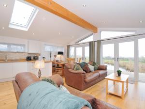 a living room with two couches and a kitchen at 15 Faraway Fields in Liskeard