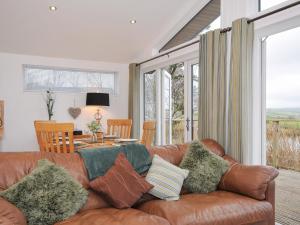 a living room with a brown leather couch with pillows at 15 Faraway Fields in Liskeard