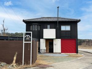 a small black house with a red garage at 海宿ニシノヤ in Shioya