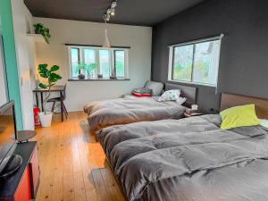 a room with three beds and a table and windows at 海宿ニシノヤ in Shioya