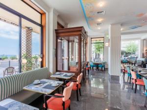 a restaurant with tables and chairs and windows at Hotel Plaza Biarritz Plage - Handwritten Collection in Biarritz