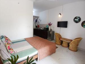 a bedroom with a bed and chairs and a television at ATS Grand Casa 02 in Greater Noida