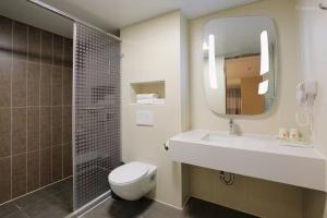 a bathroom with a sink and a toilet and a mirror at Ibis Dujiangyan in Dujiangyan
