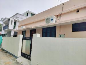 a house with a white fence and a fan at Canan suites in Trivandrum