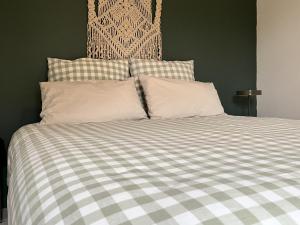 a bed with a checkered blanket and two pillows at La Estancia in Montsauche