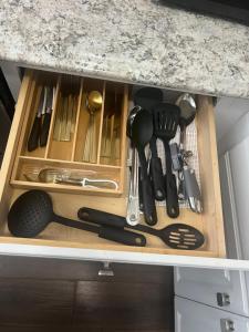 a drawer filled with cooking utensils in a cabinet at Trisuites 2 in New Orleans
