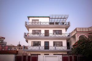 a tall white building with a balcony on it at Meera Homes in Dehradun