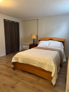 a bedroom with a bed and a night stand with a lamp at Residence Havre d'abraham in Laval