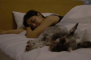 a woman laying on a bed next to a dog at sante 4073 STAY & SAUNA HAKATA ISLAND #1 AROZU in Imabari