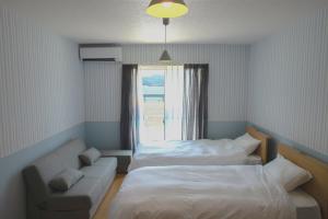 a room with two beds and a couch and a window at sante 4073 STAY & SAUNA HAKATA ISLAND #1 AROZU in Imabari