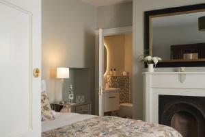a bedroom with a bed with a fireplace and a mirror at King William in Bath