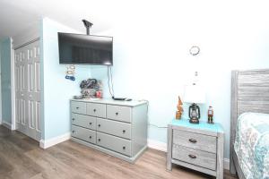 a bedroom with a bed and a dresser with a tv on it at Cedar Key Islands Dolphins Cay Condo 230 in Cedar Key