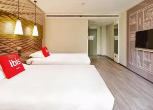 a hotel room with two beds and a flat screen tv at Ibis Dujiangyan in Dujiangyan