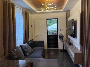 a living room with a couch and a tv at Bungalow small peaceful house in Daanbantayan