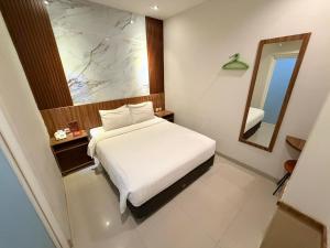 a bedroom with a white bed and a mirror at DOM Hotel Jogja in Yogyakarta