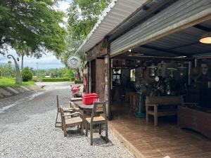 a building with a table and chairs in front of it at Wang nam yen hill วังน้ำเย็นฮิลล์ in Ban Mai