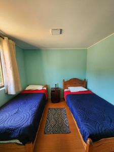 two beds in a room with blue walls at Algarrobo, house in a condominium in Algarrobo