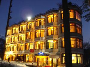 Un grand bâtiment avec des lumières allumées la nuit dans l'établissement Hotel Mountain Top, à Manali