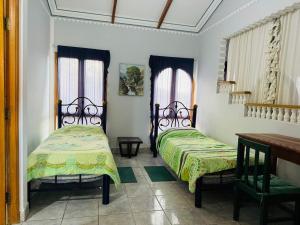 two beds in a room with two windows at Palacio Asteria in Torotoro
