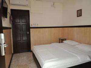 a bedroom with a white bed and a black door at House 11 in Lahad Datu