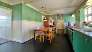 a kitchen with green walls and a wooden table and chairs at Historic Farmhouse From 1848 in Hårby