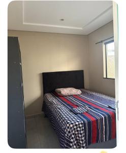 a small bedroom with a bed with a striped blanket at Apartamento Casa pontarolo in Guarapuava