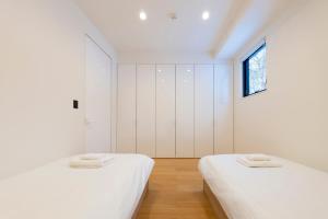 two beds in a room with white walls and a window at Kouzan Woods in Kaributo