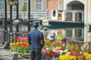 a man in a uniform standing in front of flowers at Hotel Europe Huis Ten Bosch in Sasebo