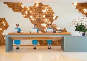 three people sitting at a desk with laptops at TMS Hotel Da Nang Beach in Danang