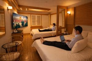 a man sitting on a couch with a laptop in a hotel room at 평촌코아 in Mabun-ni