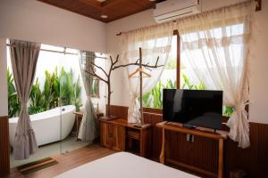 a bathroom with a tub and a tv and a bath tub at MAISON à SADEC in Ấp Tân An (2)