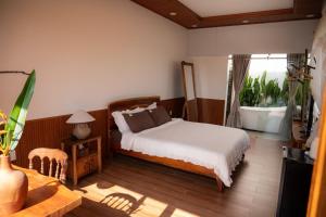 a bedroom with a bed and a table and a window at MAISON à SADEC in Ấp Tân An (2)