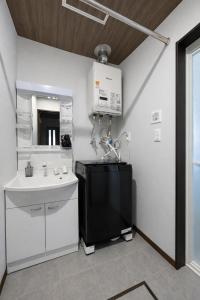 a white bathroom with a sink and a microwave at Hills Niseko C in Niseko