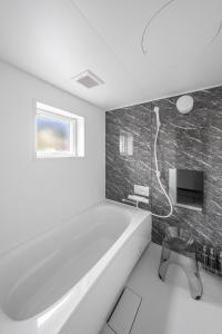 a bathroom with a bath tub and a television at Hills Niseko C in Niseko +88 photos
