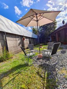 a group of chairs and a table with an umbrella at Loft Volcan Villarrica in Licán Ray