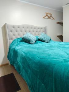a bed with a blue blanket and pillows on it at Loft Volcan Villarrica in Licán Ray