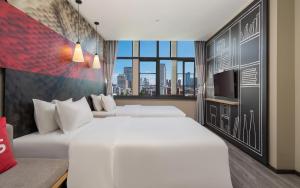 a hotel room with two beds and a tv at 宜必思昆明火车站酒店Ibis Kunming Railway Station in Kunming