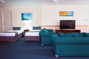 pokój hotelowy z kanapą i telewizorem w obiekcie White Lace Motor Inn w mieście Mackay