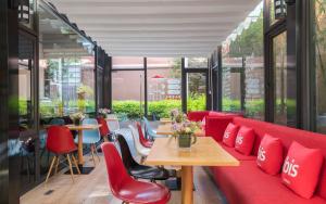 a room with a red couch and tables and chairs at 宜必思昆明火车站酒店Ibis Kunming Railway Station in Kunming