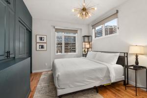 a bedroom with a white bed and a chandelier at Rooftop Retreat with Workspace and BBQ in Denver