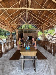 a group of three women sitting at a table on the beach at Frits Homestay in Kri