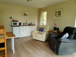 a living room with two chairs and a kitchen at Lily Pad Apartment in Motueka +17 photos
