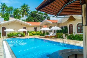a villa with a swimming pool in front of a house at Jacks Resort in Vagator