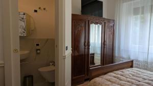 a bathroom with a toilet and a wooden cabinet at AL78 guesthouse in Biella