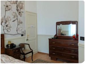 a bedroom with a dresser and a mirror and a chair at AL78 guesthouse in Biella