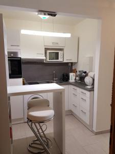 a kitchen with a white counter and a stool in it at Apartment am Kaiserplatz in Düren - Eifel
